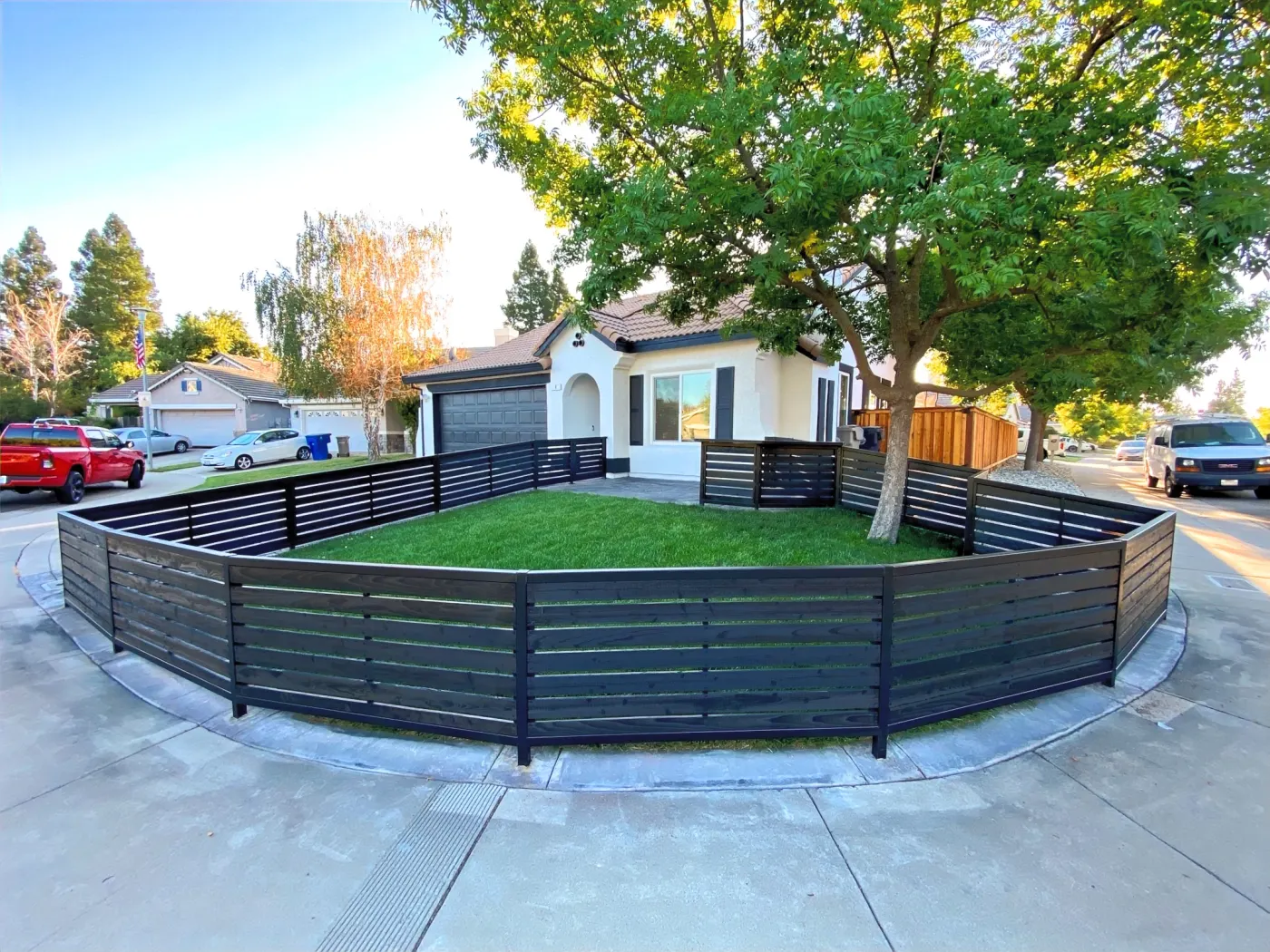 Front lawn enclosed by a low black horizontal metal fence with matching gates