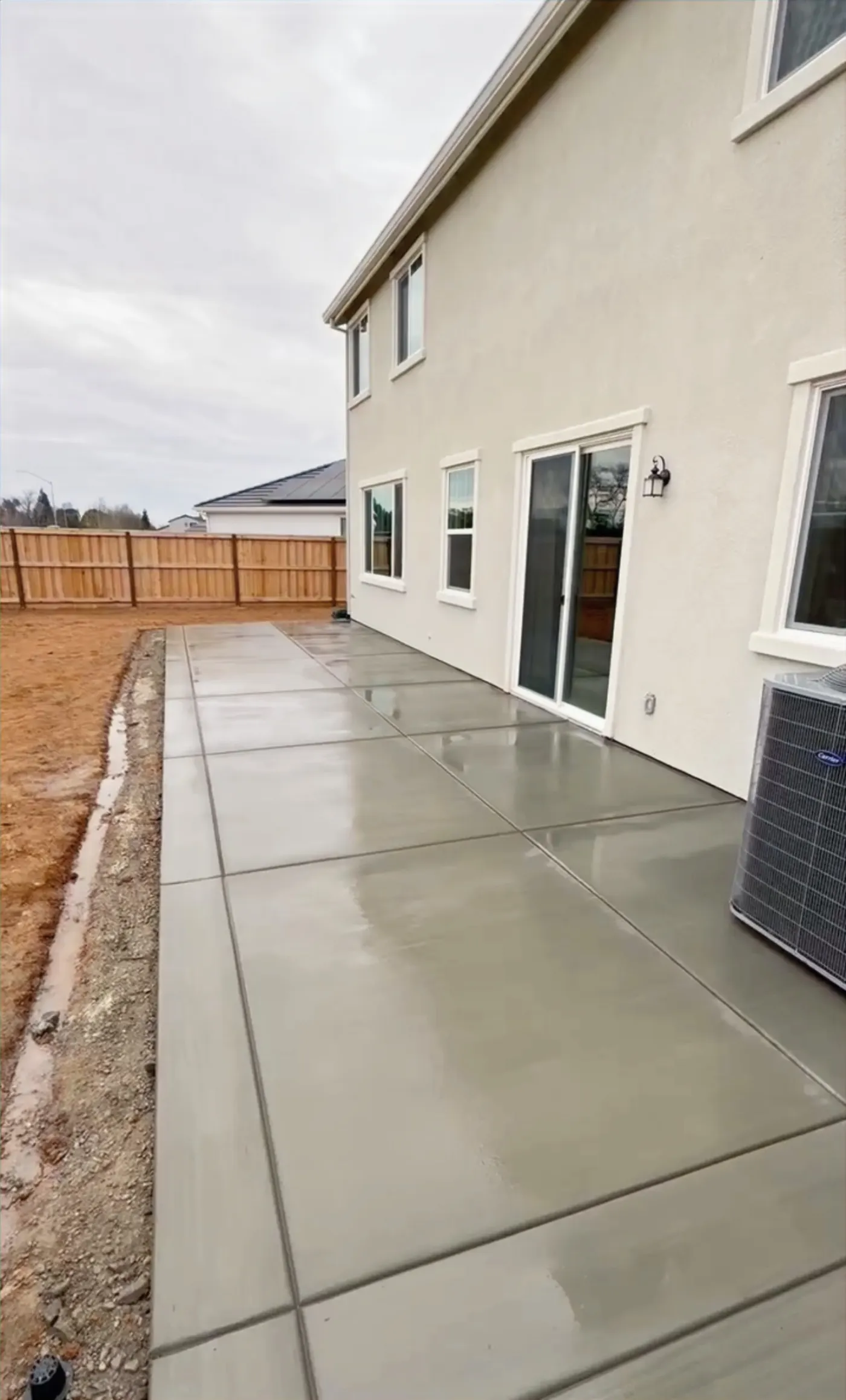 Finished concrete walkway between a house and wood fence