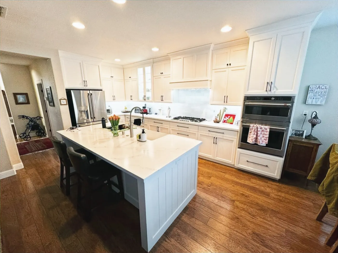 Bright white kitchen with a large center island, black counter stools, and wood flooring